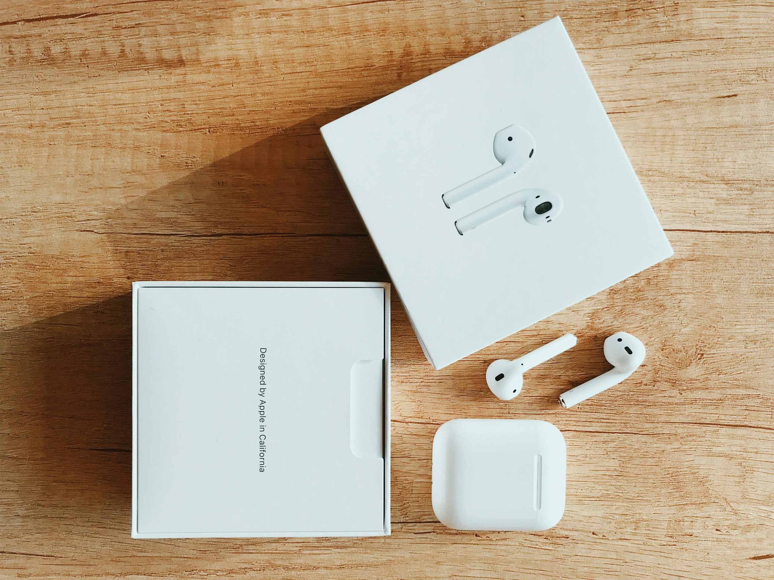 Top view of wireless earbuds with packaging on a wooden surface.